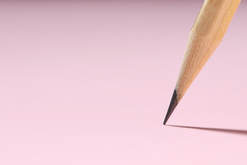 One graphite pencil on pink background, closeup. Space for text