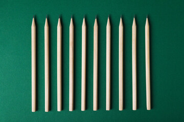 Many graphite pencils on green background, flat lay