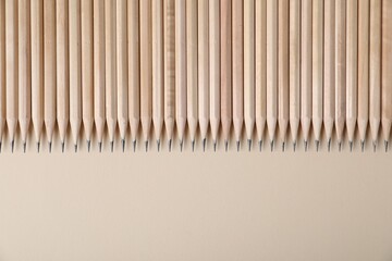 Many graphite pencils on beige background, flat lay. Space for text