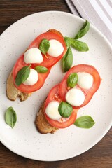 Tasty sandwiches with mozzarella cheese, tomatoes and basil on wooden table, top view