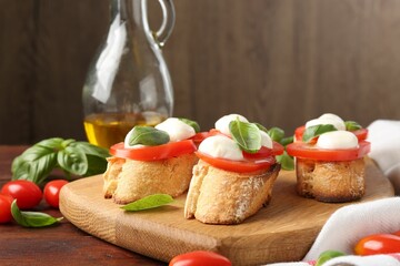 Tasty sandwiches with mozzarella cheese, tomatoes and basil on wooden table, closeup