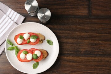 Tasty sandwiches with mozzarella cheese, tomatoes and basil on wooden table, flat lay. Space for text