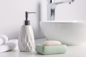 Soap bar, bottle of cosmetic product and towels on white countertop indoors, closeup
