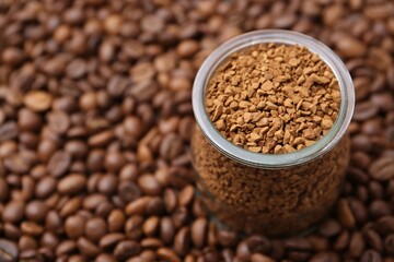 Glass jar with granulated instant coffee on beans, closeup. Space for text