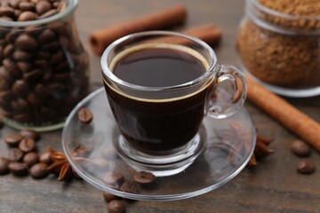 Cup of aromatic coffee, beans, instant powder and spices on wooden table, closeup