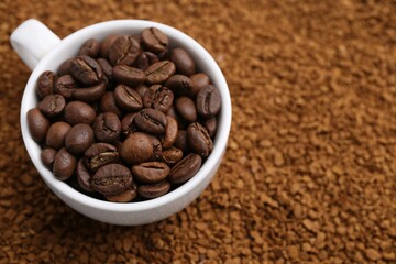 Cup of roasted beans on granulated instant coffee, closeup. Space for text