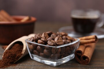 Roasted beans, instant coffee powder and cinnamon sticks on wooden table against brown background, closeup