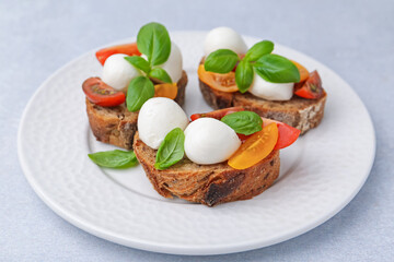 Tasty sandwiches with mozzarella cheese, tomatoes and basil on white table, closeup