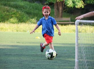  little three-year-old boy plays football at a sports school .