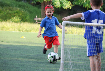  little three-year-old boys plays football at a sports school with a coach.