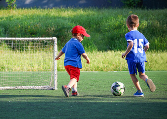 little three-year-old boys plays football at a sports school with a coach.