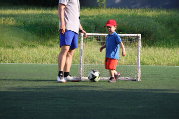  little three-year-old boy plays football at a sports school with a coach.