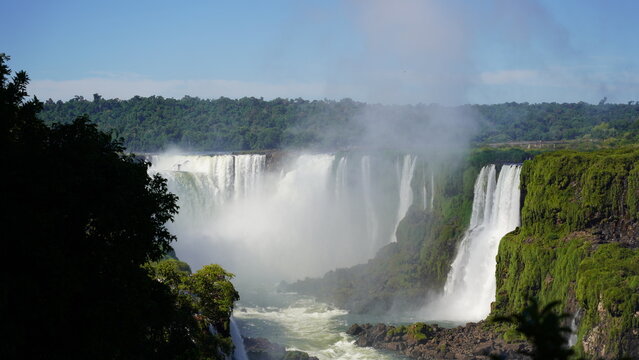 Stunning view of Iguazu Falls cascading through lush rainforest on the border of Brazil and Argentina, showcasing powerful waterfalls, mist, and vibrant natural beauty
