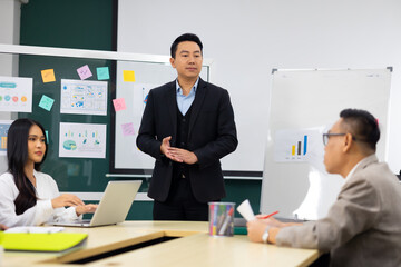 Presentation - Asian business man people giving presentation and Report pointing at white board. People Work in Business Office.