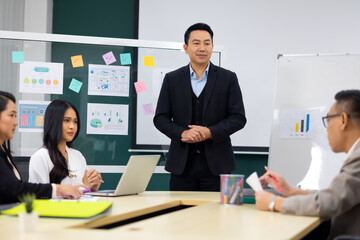 Presentation - Asian business man people giving presentation and Report pointing at white board. People Work in Business Office.