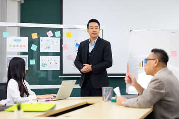 Presentation - Asian business man people giving presentation and Report pointing at white board. People Work in Business Office.