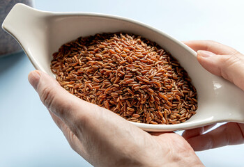 Woman's hands holding uncooked raw flax seeds in a bowl
