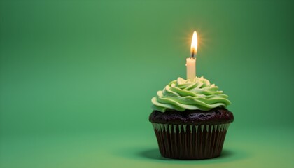 A chocolate cupcake with green frosting and a lit candle on a green background