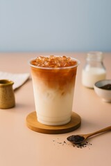 Refreshing Iced Milk Tea with Creamy Layers and Ice Cubes in a Clear Cup on a Soft Pastel Background