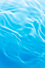 Close-up of blue water surface background,Close-up view of rippling blue water with sunlight reflections on a swimming pool surface, creating a calming abstract pattern.