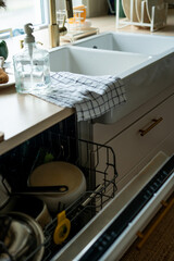 Open dishwasher with various plates. Bright kitchen interior.