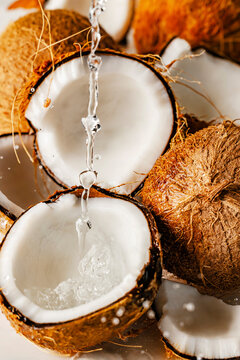 Close-up of halved coconuts with water being poured into one of them.