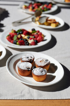Mini almond cakes with blueberries, fruit plate with blueberries, strawberries, boysenberries, pineapple, rockmelon / cantaloupe and mint, and a plate of flourless orange cake