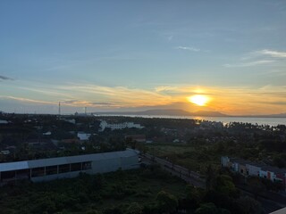 Panoramic sunrise over a city and bay with a vibrant yellow sky. 