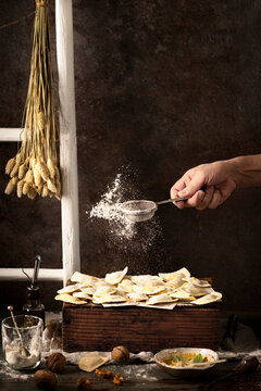 home made ravioli with nut sauce, traditional from liguria Italy woman's hand sprikling flour with sifter