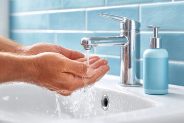 Person Washing Hands with Water at Bathroom Sink