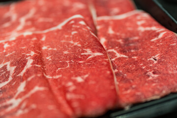A close up detailed image of sliced Japanese wagyu beef in a black plate prepared for Shabu Shabu