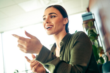 Confident Young Businesswoman Engaged in Conversation at a Well-Lit Workspace, Showcasing...