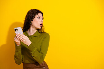 Young woman with vibrant background holding smartphone while looking off-camera expressing...