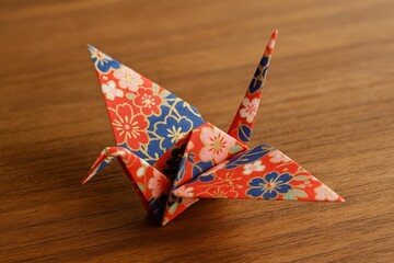 Colorful origami crane crafted from decorative paper resting on a wooden surface