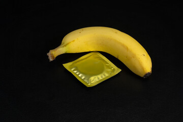A condom next to a banana with a black background