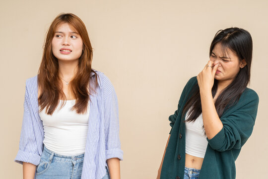 Woman covering her nose after her friend farted