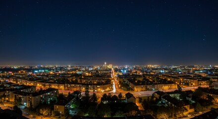 Obraz premium Panoramic night cityscape view; illuminated streets, buildings, and starry sky