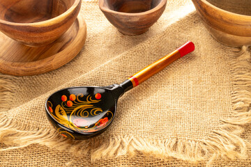 One painted wooden spoon with wooden utensils on jute cloth, close-up.