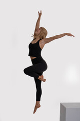 Dancer Toni in the studio dancing Dancer Toni in the studio dancing with motion and light - The image depicts a dancer captured mid-air in a striking pose. They are dressed in a black tank top and bla