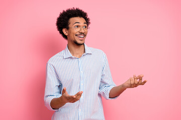 Cheerful young man with expressive gestures against pink background exuding positivity and casual elegance in fashion