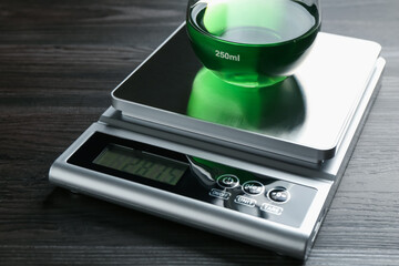 Laboratory scale with flask of sample on wooden table, closeup