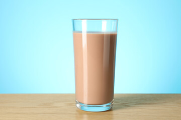 Tasty chocolate milk in glass on wooden table against light blue background