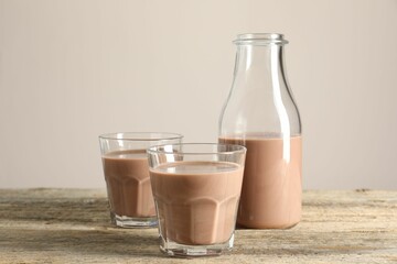 Tasty chocolate milk in glasses and bottle on wooden table