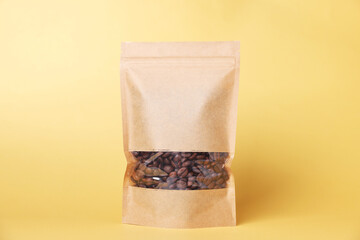 One zipper stand-up pouch with coffee beans on light orange background. Mockup for design