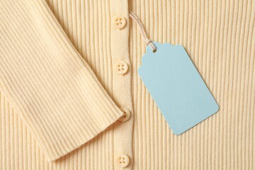Cardboard tag on beige garment, top view