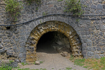 Oval dark entrance to the ancient cave outside