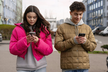 Teenagers using smartphones while walking down the street