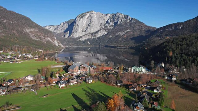 Aerial view of Altausseer See and village surrounded by mountains reflecting in calm alpine waters. Austria, Salzkammergut. 2x speeded up from 30 fps.