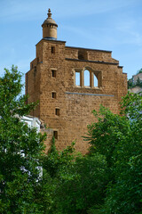 Historical Stone Tower Surrounded by Green Foliage Under a Bright Blue Sky