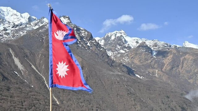 Nepali flag blowing by the wind against the blue sky in Langtang national park, Nepal. The crimson red is Nepal's national color, and it indicates the brave spirits of the Nepalese people.